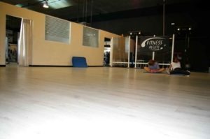 sala con personas haciendo ejercicio en la sala sobre una superficie de tarima clara. Al fondo se ve la sala de boxeo. Zona de Alcobendas. Gimnasio en Algete cerca de Cobeña